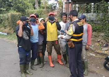 Aiptu Kemiran, membagikan masker kepada warga di jalan Hasan Saputra IV, Kel Turangga, Kec Lengkong, Kota Bandung, Selasa (20/10/2020)