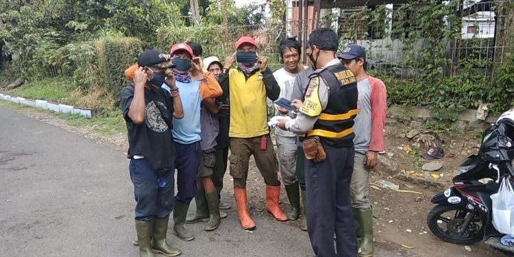 Aiptu Kemiran, membagikan masker kepada warga di jalan Hasan Saputra IV, Kel Turangga, Kec Lengkong, Kota Bandung, Selasa (20/10/2020)