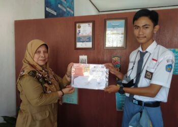 Teks foto: Kepala Sekolah SMKN 8 Pandeglang, Dra. Ida Maherani Widaningsih baru-baru ini menyerahkan piagam penghargaan literasi dari Alabama Lestari Indonesia kepada salah satu anak didiknya, Ahmad Bukhori (Foto: Istimewa).