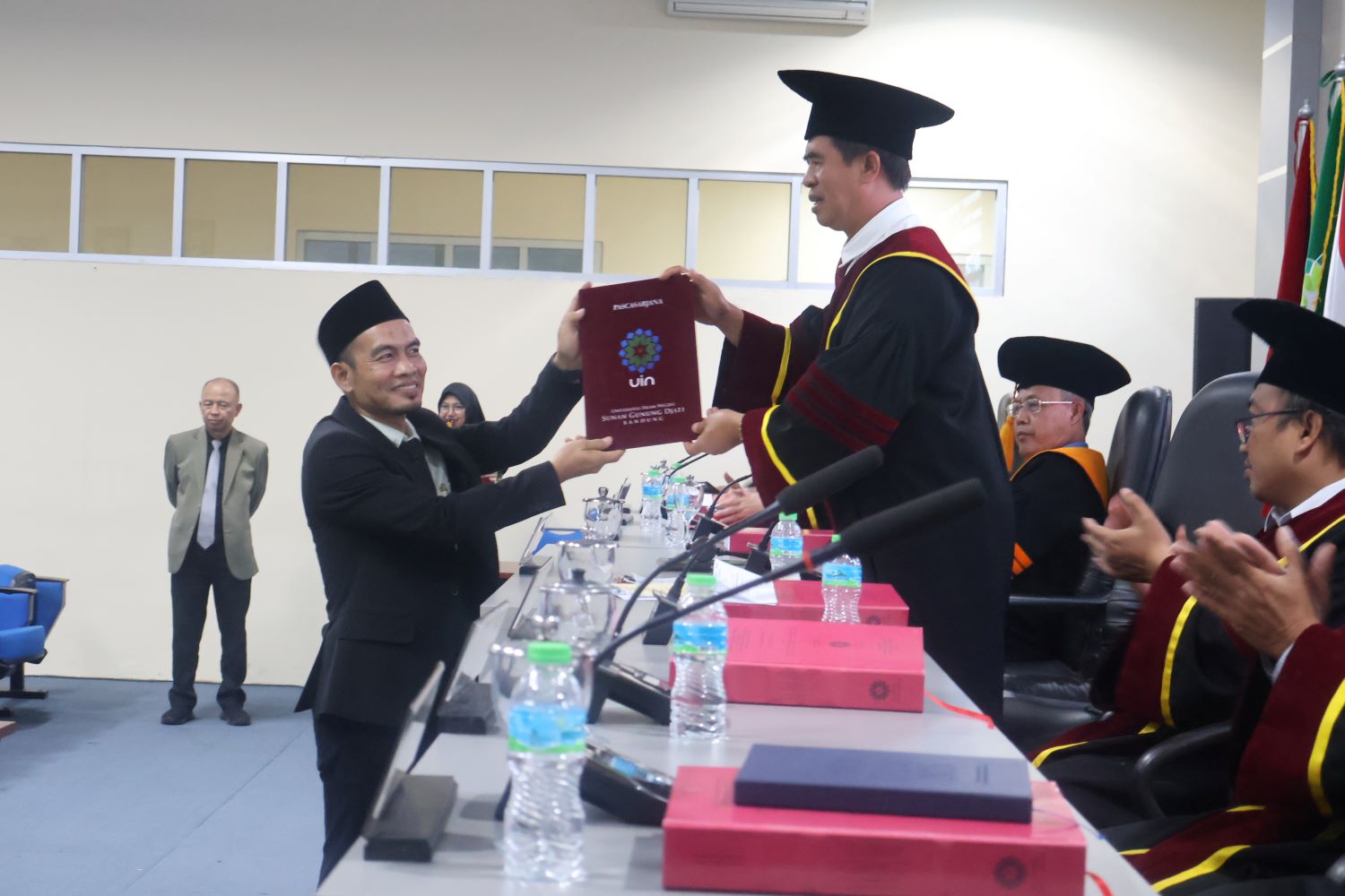 Mohamad Rana menerima sertifikat lulus ujian promosi doktor dari ketua Tim penguji sidang senat ujian doktor pascasarjana UIN SGD Bandung, Jumat,(29/08)/bedanews.com/dedy brajamusti