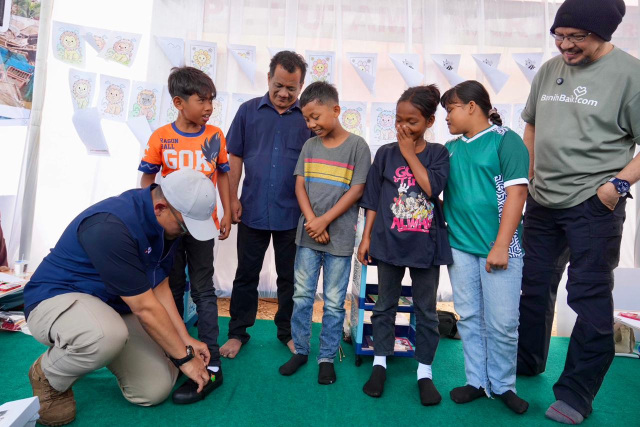 PEDULI-Wakil Bupati Aceh Tamiang, Ismail menyaksikan penyerahan sepatu bagi anak penghuni Huntara Aceh Tamiang oleh Direktur Utama PTPN IV PalmCo. Selain menyiapkan lahan untuk pembangunan hunian, dukungan psikososial dan peluncuran Sekolah Darurat bekerjasama dengan benihbaik.com yang didirikan oleh Andy F Noya. (Foto Ist).