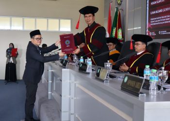 FOTO : Ilham Mujahid ketika menerima sertifikat kelulusan sidang promosi doktor dari ketua sidang  di Pascasarjana UIN Bandung,Selasa, (12/5/2026)/bedanews.com
