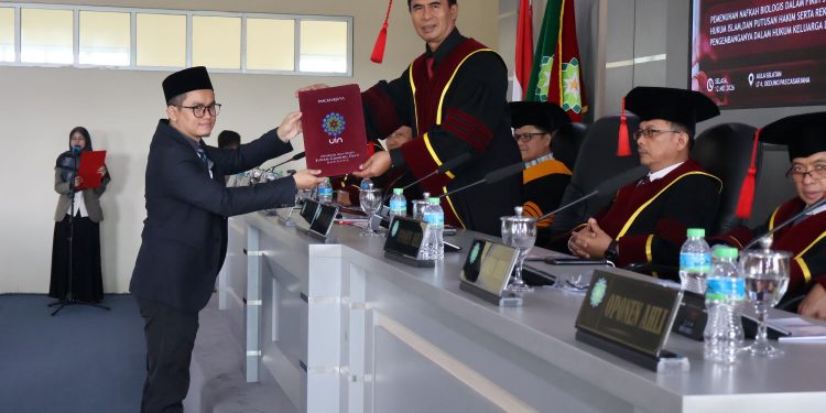 FOTO : Ilham Mujahid ketika menerima sertifikat kelulusan sidang promosi doktor dari ketua sidang  di Pascasarjana UIN Bandung,Selasa, (12/5/2026)/bedanews.com